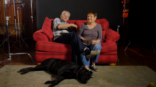 Allen and Rosemary on the couch with black dog at their feet.